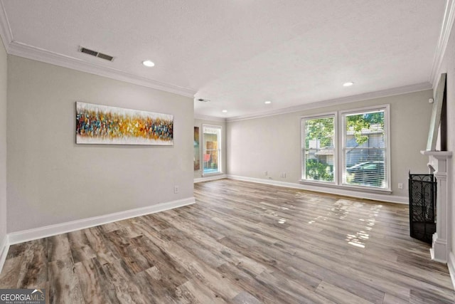 unfurnished living room featuring ornamental molding, a textured ceiling, a fireplace, and light wood-type flooring