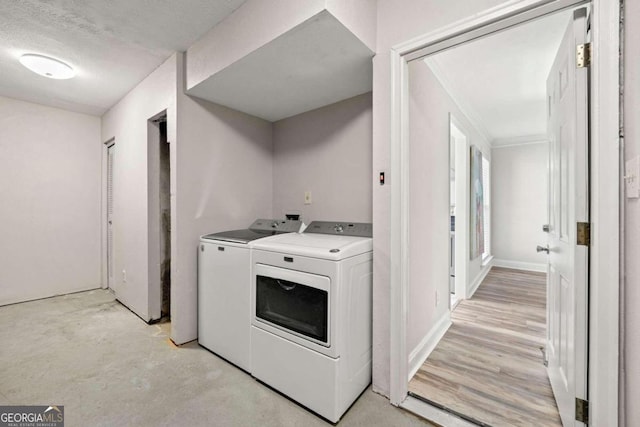 laundry area featuring light hardwood / wood-style floors, crown molding, a textured ceiling, and washer and clothes dryer