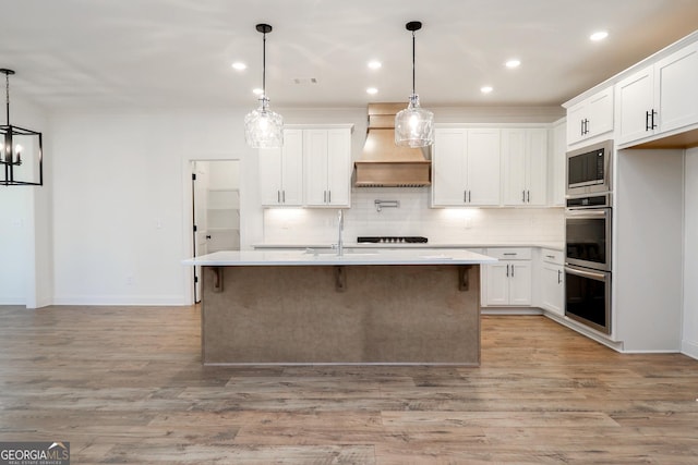 kitchen with tasteful backsplash, built in microwave, light countertops, custom exhaust hood, and a sink