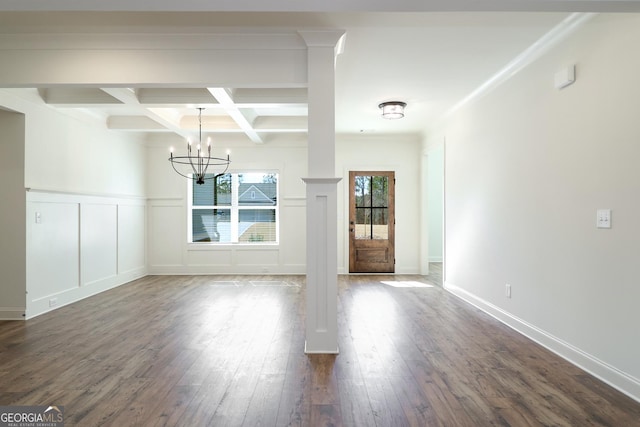 unfurnished dining area featuring coffered ceiling, dark wood-type flooring, beamed ceiling, a decorative wall, and a chandelier