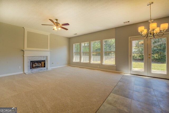 unfurnished living room with a textured ceiling, a premium fireplace, carpet floors, and ceiling fan with notable chandelier