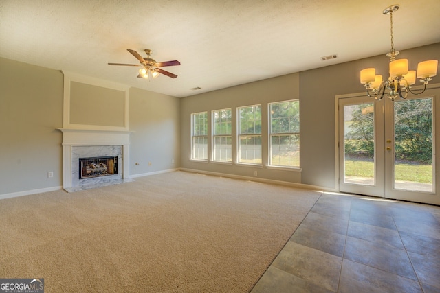 unfurnished living room with baseboards, a chandelier, a ceiling fan, and a high end fireplace