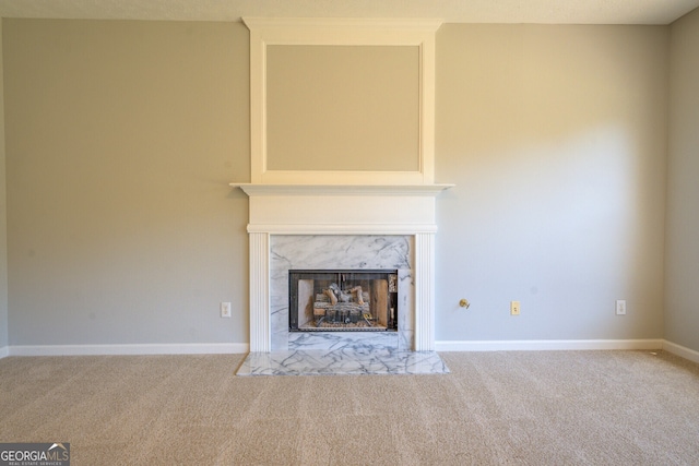 unfurnished living room featuring carpet floors, a high end fireplace, and baseboards