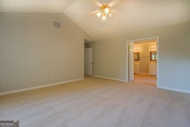 unfurnished bedroom featuring light colored carpet, lofted ceiling, baseboards, ensuite bathroom, and a ceiling fan