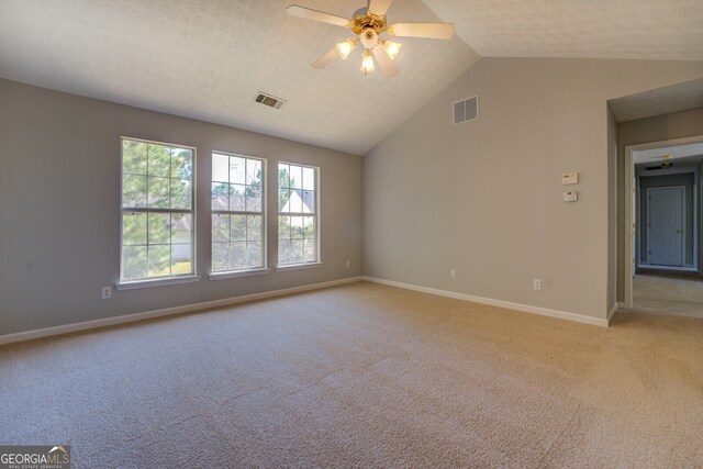 carpeted empty room with a textured ceiling, ceiling fan, and vaulted ceiling