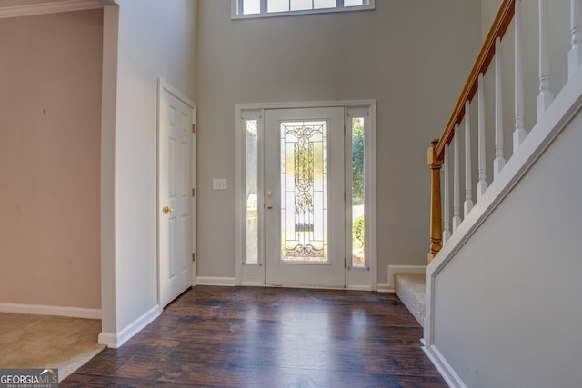 entryway featuring stairway, a towering ceiling, wood finished floors, and baseboards