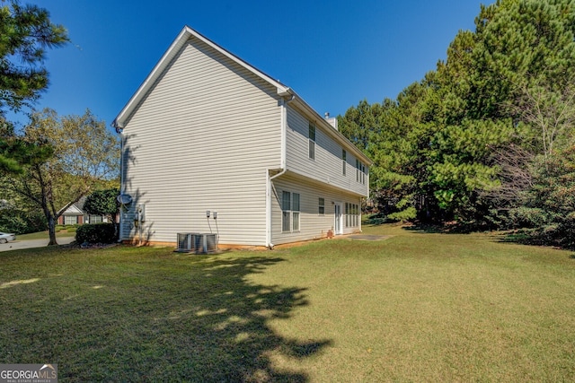 view of side of home with central AC and a yard