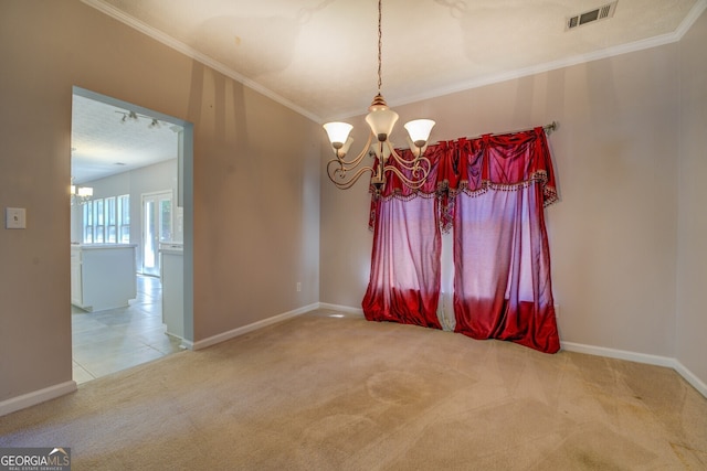 spare room with a chandelier, carpet flooring, crown molding, and baseboards