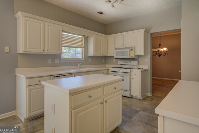 kitchen with a kitchen island, sink, pendant lighting, a chandelier, and white appliances