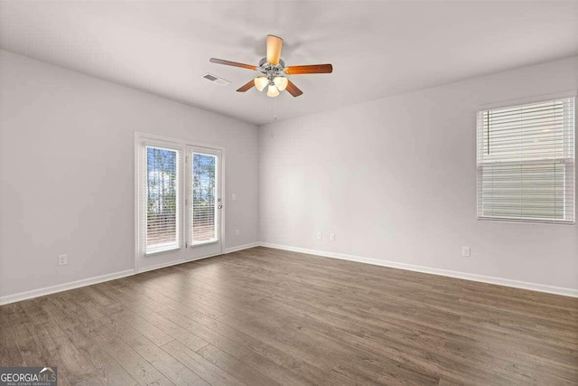 empty room with ceiling fan and dark hardwood / wood-style flooring