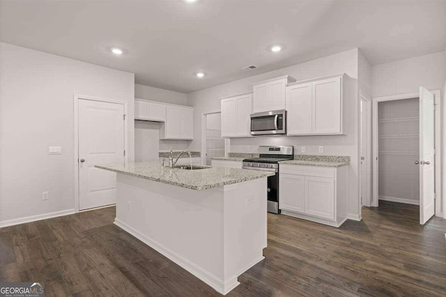 kitchen with sink, white cabinetry, appliances with stainless steel finishes, dark hardwood / wood-style floors, and an island with sink