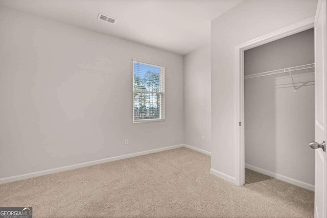 unfurnished bedroom with light carpet and a closet