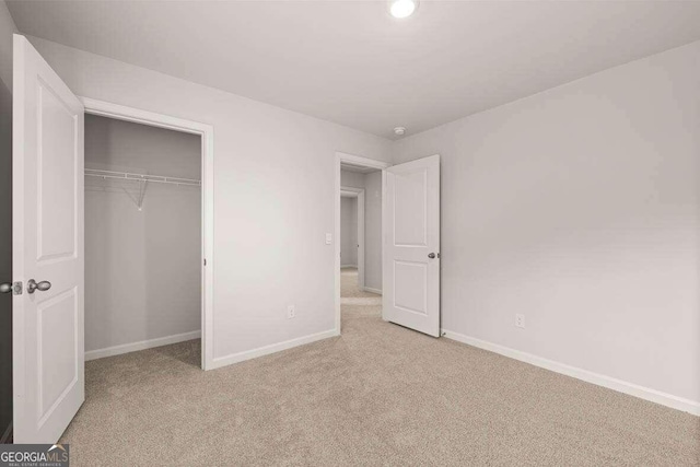 unfurnished bedroom with light carpet and a closet