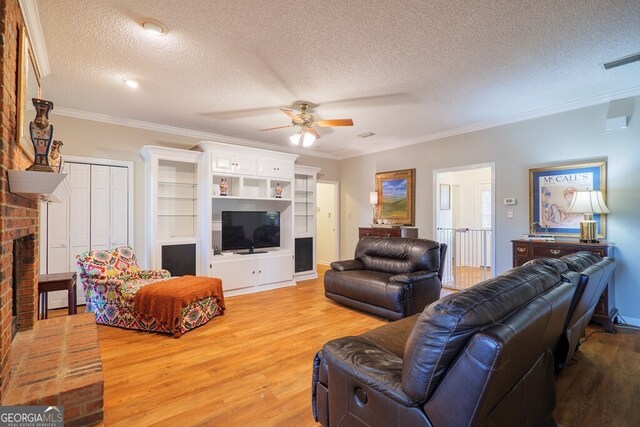 living room with ceiling fan, a textured ceiling, hardwood / wood-style flooring, ornamental molding, and a fireplace