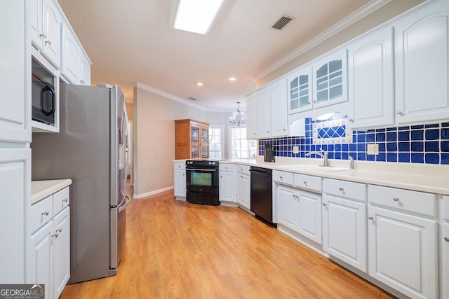 kitchen with light hardwood / wood-style flooring, ornamental molding, black appliances, sink, and white cabinetry