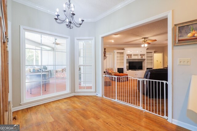 interior space featuring hardwood / wood-style flooring, a textured ceiling, ornamental molding, and ceiling fan with notable chandelier