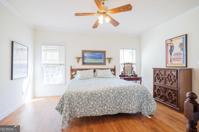 bedroom featuring ceiling fan, hardwood / wood-style flooring, a textured ceiling, and crown molding