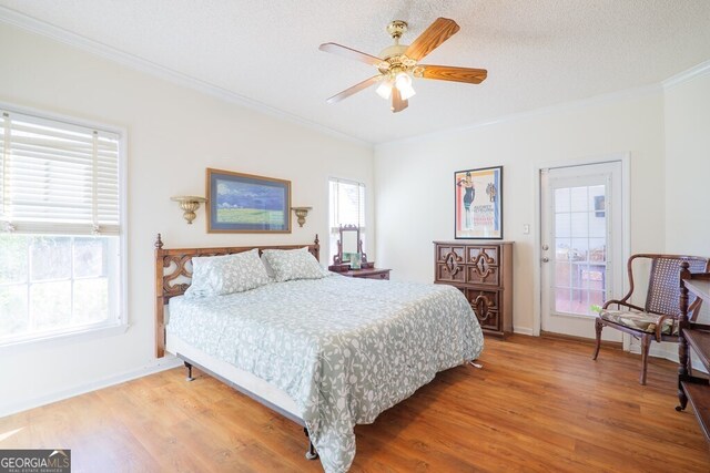 bedroom with a textured ceiling, crown molding, wood-type flooring, and ceiling fan