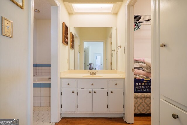 bathroom with vanity, hardwood / wood-style flooring, and a tub