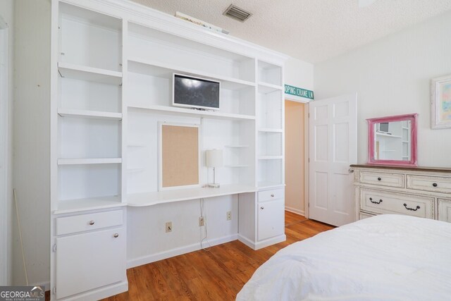 bedroom with light hardwood / wood-style floors and a textured ceiling