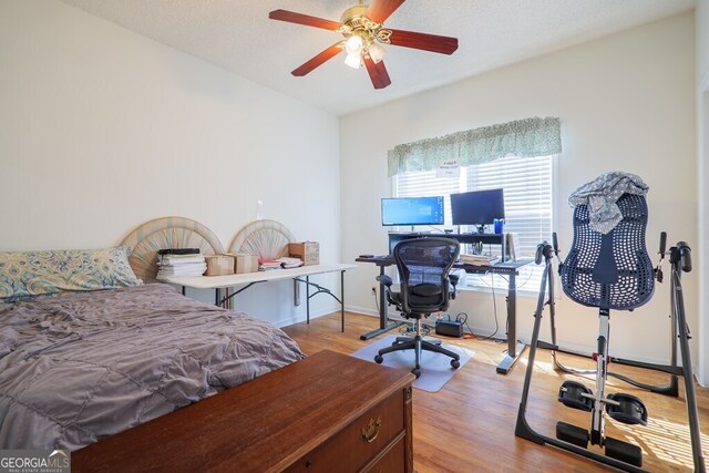 bedroom with a textured ceiling, light wood-type flooring, and ceiling fan