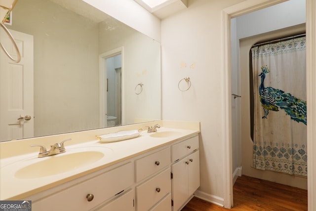 bathroom with hardwood / wood-style floors, toilet, a skylight, vanity, and curtained shower