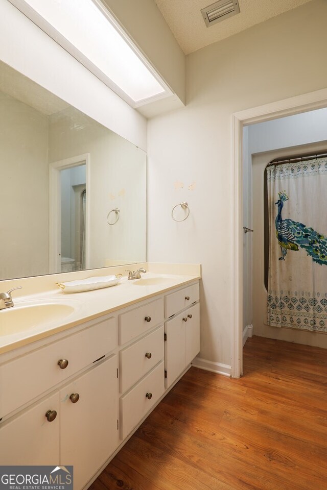 bathroom featuring vanity, hardwood / wood-style flooring, and a textured ceiling