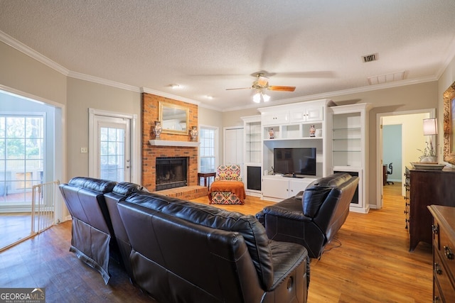 living room with crown molding, wood-type flooring, a textured ceiling, and a brick fireplace