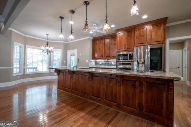 kitchen with light hardwood / wood-style flooring, a notable chandelier, stainless steel appliances, and crown molding