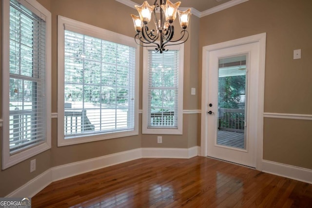 unfurnished dining area with a wealth of natural light, ornamental molding, a notable chandelier, and wood-type flooring