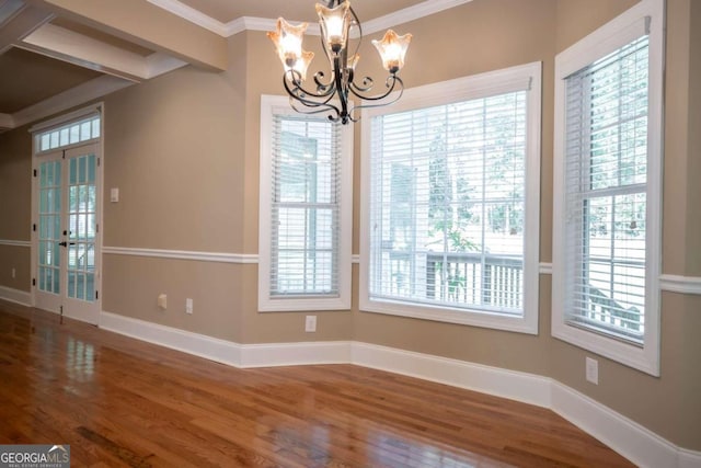 unfurnished dining area with crown molding, hardwood / wood-style flooring, and an inviting chandelier