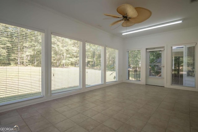 unfurnished sunroom featuring ceiling fan and a healthy amount of sunlight