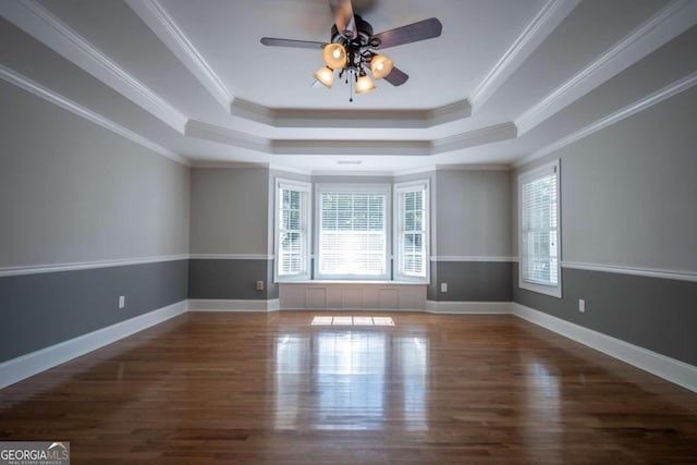 spare room featuring dark wood-type flooring, ceiling fan, ornamental molding, and a tray ceiling