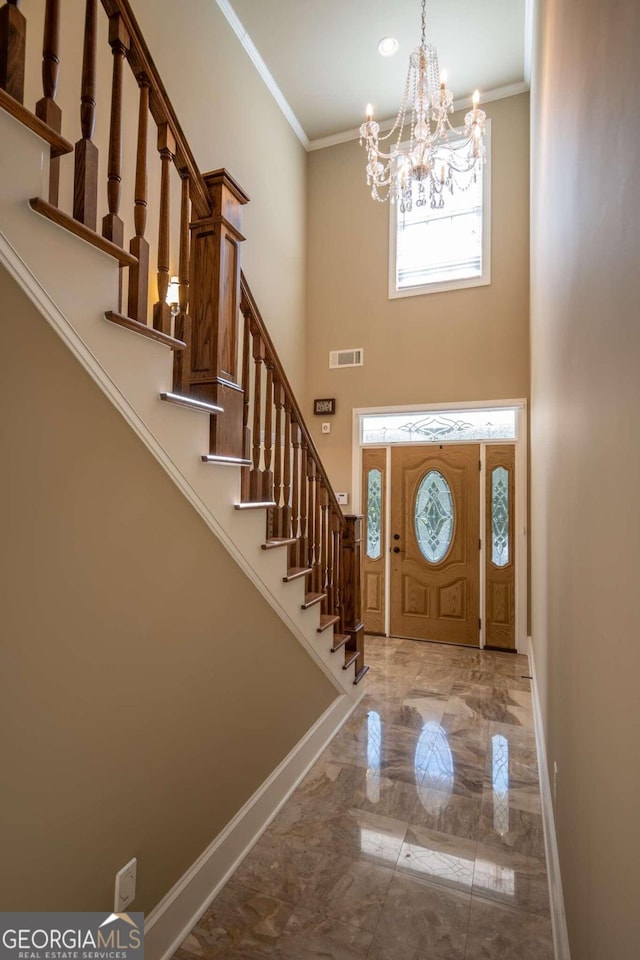 entryway with crown molding, a notable chandelier, and a high ceiling