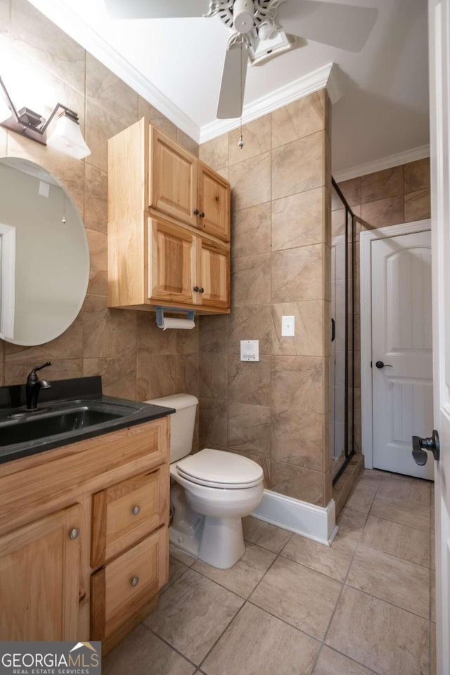 bathroom featuring a shower with shower door, toilet, ceiling fan, vanity, and ornamental molding