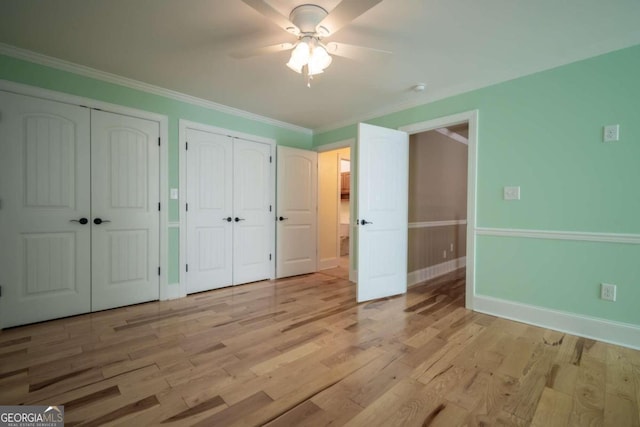 unfurnished bedroom featuring multiple closets, light hardwood / wood-style flooring, ornamental molding, and ceiling fan