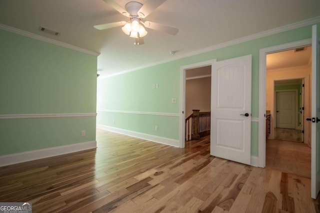 empty room with ceiling fan, crown molding, and hardwood / wood-style floors