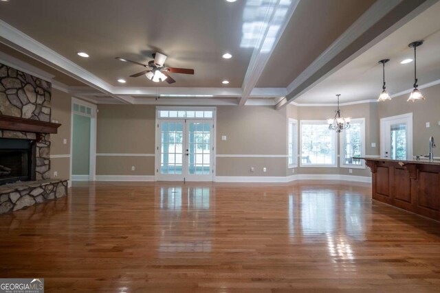 living room featuring hardwood / wood-style floors, ceiling fan with notable chandelier, a fireplace, crown molding, and french doors