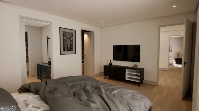 bedroom with ensuite bathroom and light hardwood / wood-style flooring