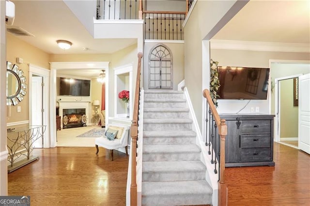 staircase featuring ornamental molding and hardwood / wood-style flooring