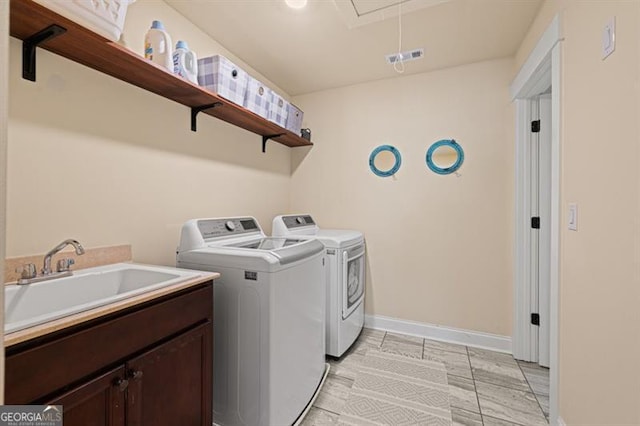 clothes washing area with a sink, baseboards, independent washer and dryer, cabinet space, and attic access