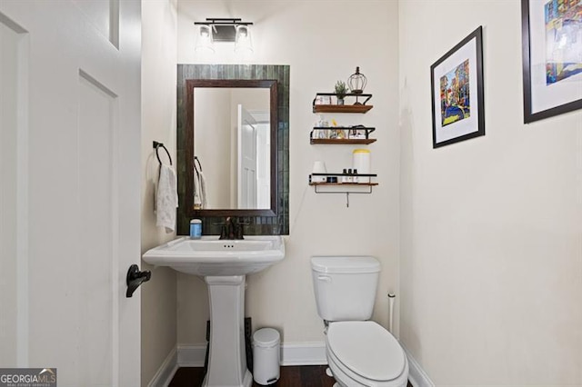 half bathroom with toilet and baseboards