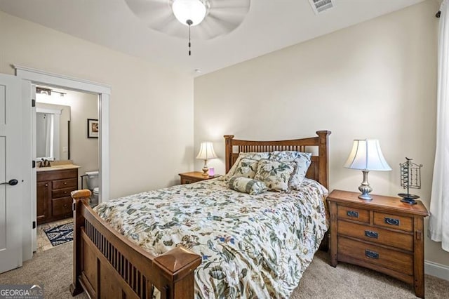 bedroom with visible vents, ensuite bathroom, a ceiling fan, and light colored carpet