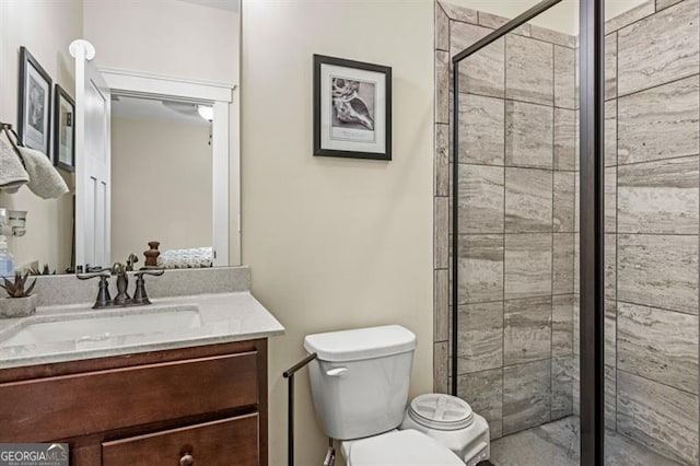 bathroom with vanity, a shower with door, and toilet