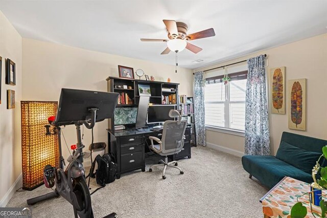 office space with light colored carpet, ceiling fan, and baseboards