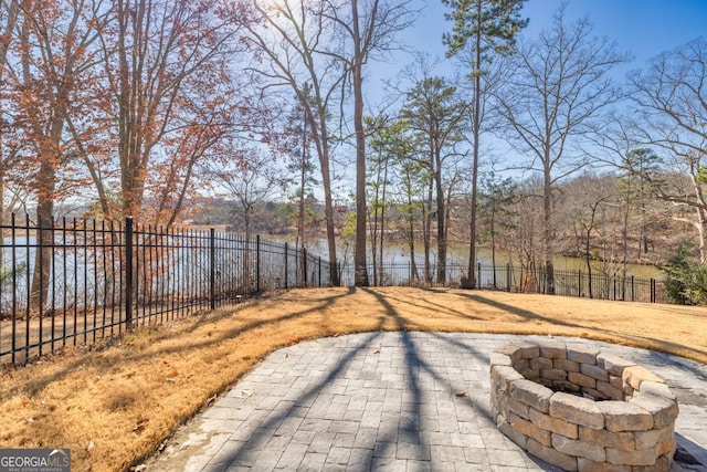 view of yard featuring a fire pit, a patio area, a water view, and a fenced backyard