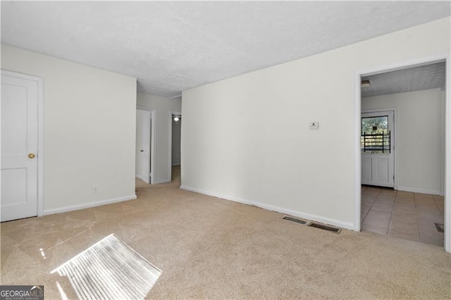 empty room with light carpet and a textured ceiling