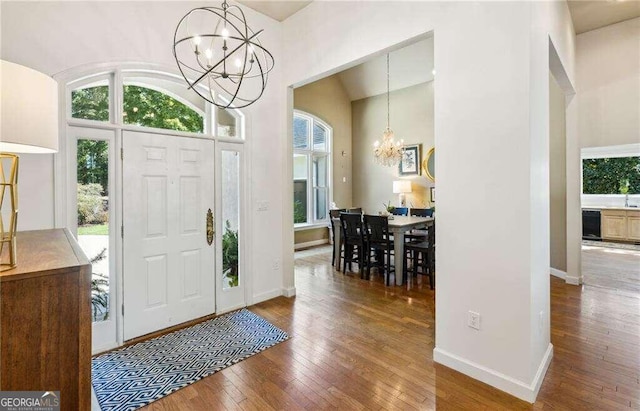 foyer with a chandelier, wood-type flooring, and a high ceiling