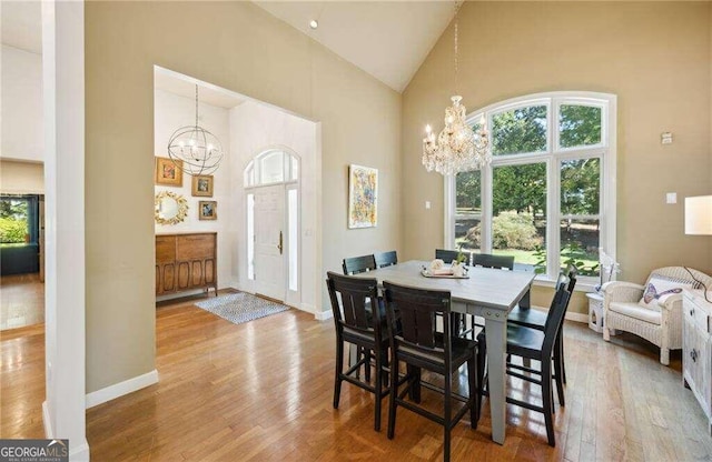 dining area featuring a notable chandelier, light hardwood / wood-style floors, and high vaulted ceiling