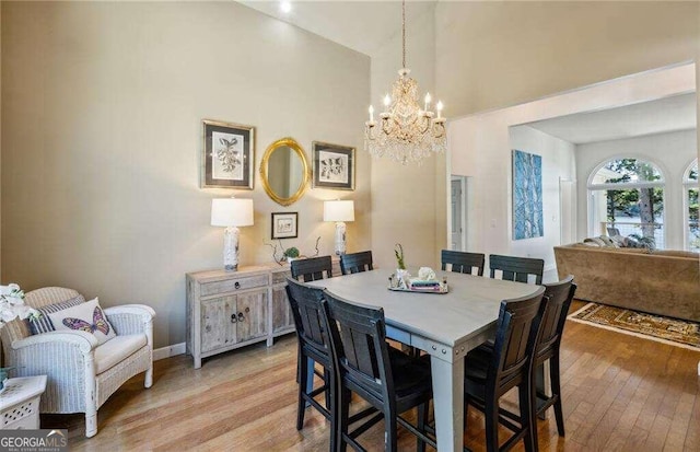 dining space with light hardwood / wood-style floors and an inviting chandelier